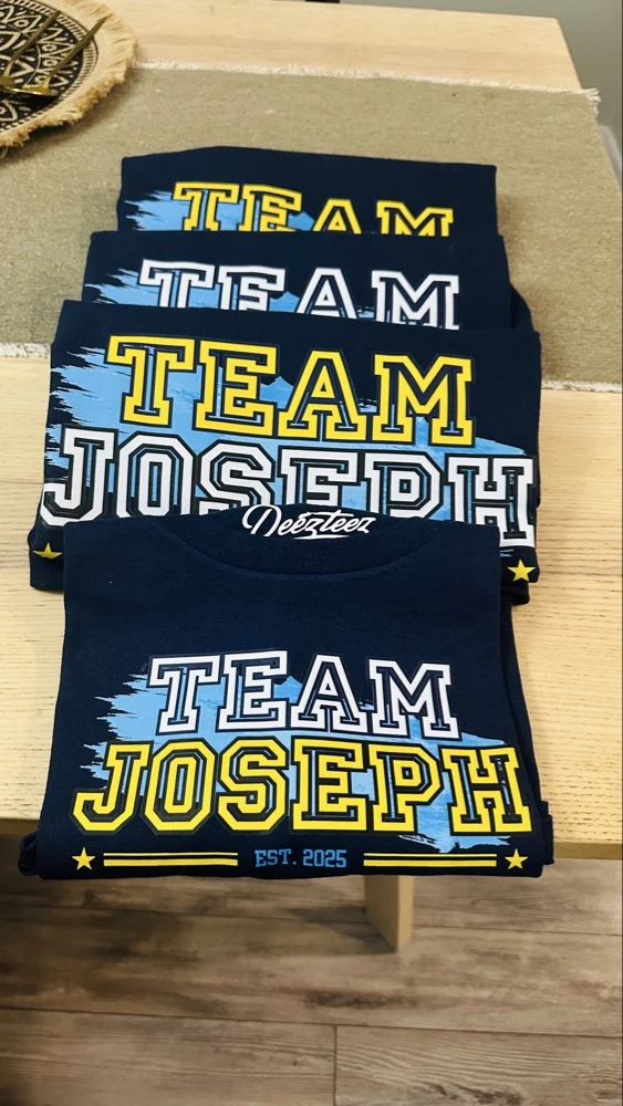 Finished Team Joseph family shirts with yellow, white and blue lettering, folded together.
